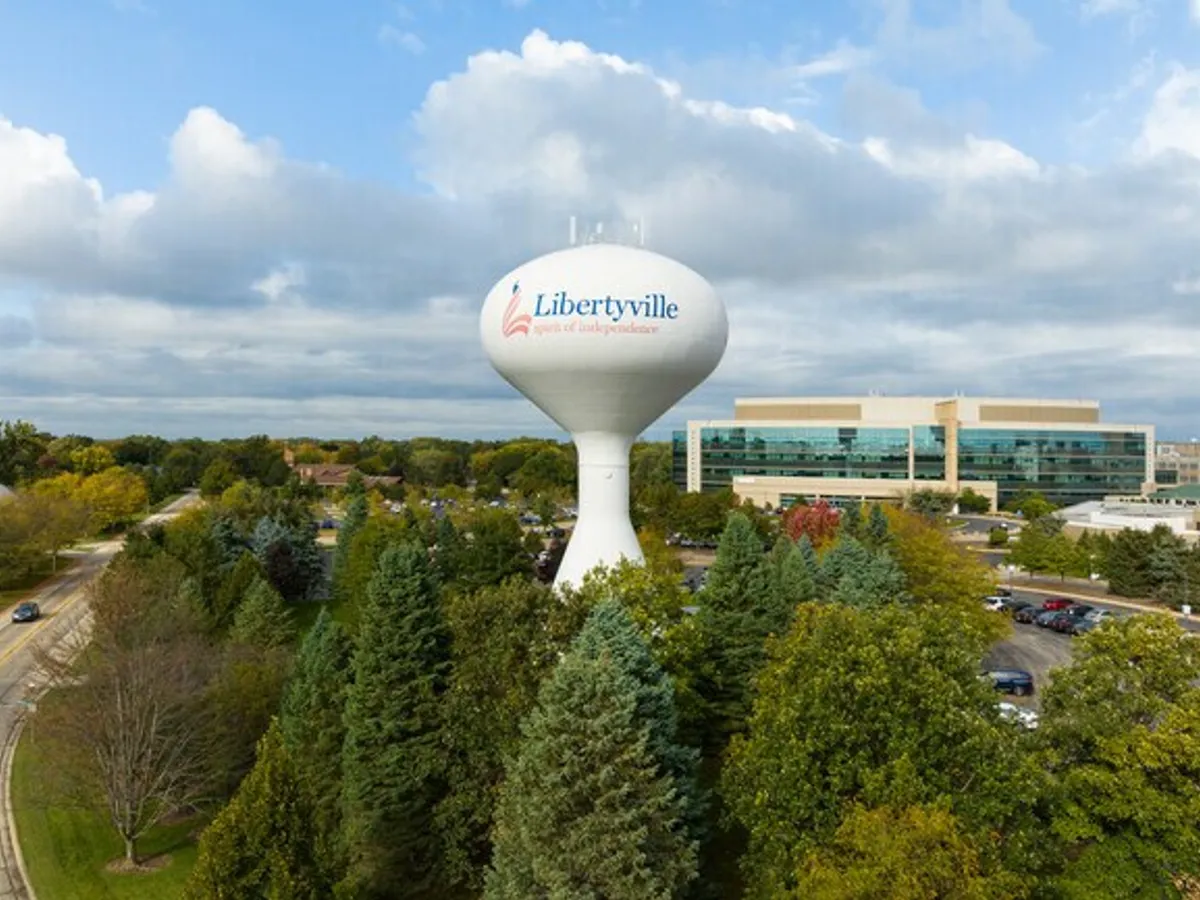 Aerial view of the Libertyville, IL water tower above the treeline, office buildings behind it